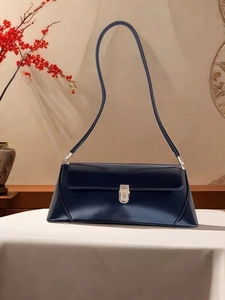 Close-up of minimalist black leather shoulder bag with a silver metal swivel lock