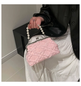 Detailed close-up of pink textured fabric shell bag with pearl handle and metal clasp