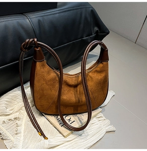 Détail du sac croissant en daim marron avec poignée en cuir nouée et bordure lisse