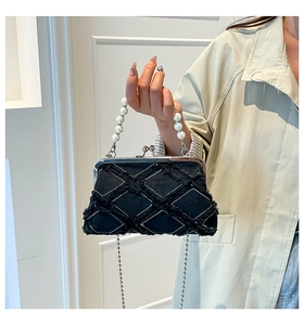 Detail of black canvas shell bag with diamond quilting and pearl bead handle
