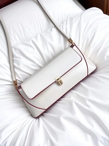 Macro detail of a white baguette bag featuring burgundy edges and a gold metal clasp