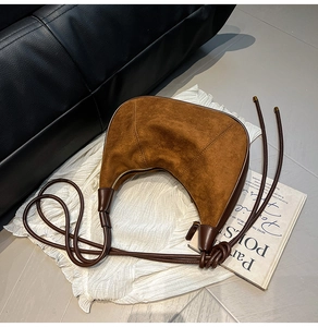 Détail d'un sac hobo en daim caramel avec coutures et fermeture sur un magazine