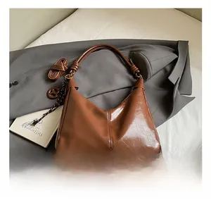 Detail of vintage dark brown glossy leather hobo bag with knotted strap and weave charm