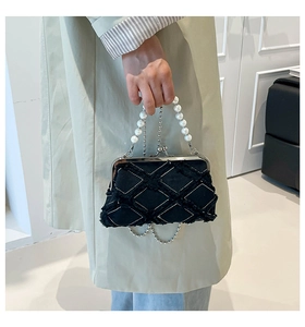 Detailed shot of black quilted shell bag with pearl handle and metal clasp closure