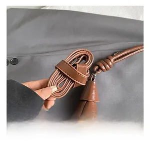 Detail shot of the adjustable brown faux leather shoulder strap with fine stitching