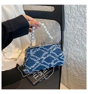 Detail of vintage denim shell bag with frayed fringe texture and pearl bead handle