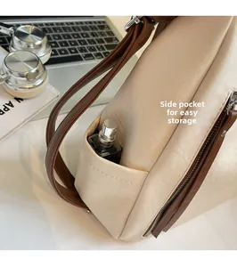 Detailed close-up of side pocket on beige faux leather bag showing storage for a perfume bottle