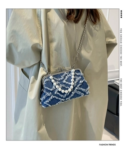 Detailed close-up of blue denim vintage clasp bag with pearl strap and metal chain