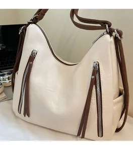 Detail of the textured off-white leather tote featuring decorative brown zipper pockets