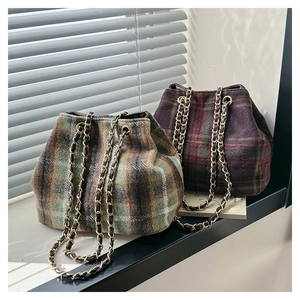 Detail of plaid wool bucket bags with drawstring closure and metal chain straps