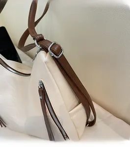 Detail of cream leather bag with brown adjustable strap and silver metal buckle hardware