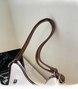 Detailed close-up of smooth stitching and silver metal buckle on cream shoulder bag straps