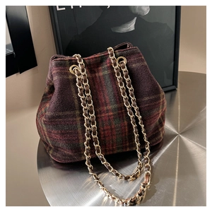 Detailed macro view of the wool plaid fabric texture and golden metal chain strap