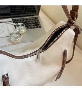Close-up of smooth silver zipper and textured white leather on a commute tote bag