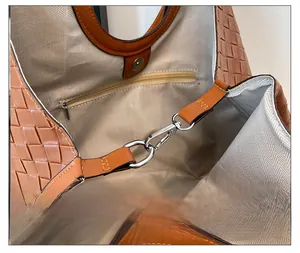 Detail of silver twist lock and herringbone lining inside brown woven tote bag