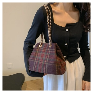 Detail of vintage plaid wool shoulder bag with golden metal chain strap on model