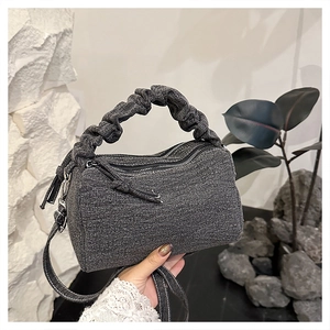 Detail of grey denim pillow bag with scrunchie handle and double zip closure