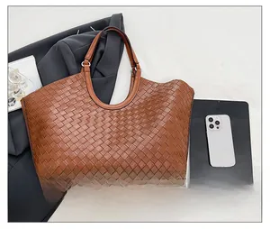 Detailed close-up of woven brown leather tote bag with premium cross-stitch texture
