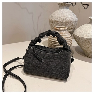 Detailed view of dark grey cylinder bag with scrunchie handle and denim texture finish