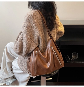 Brown soft leather tote bag featuring stylish side tassel detail and silver zipper accents