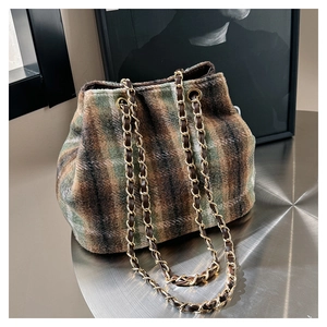 Close-up of wool plaid shoulder bag with luxury gold chain strap and vintage texture