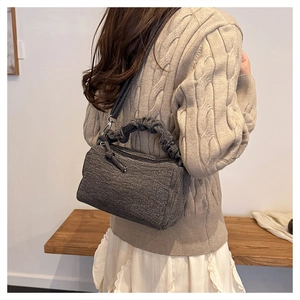 Detailed view of gray fabric crossbody bag texture with pleated handle and slim shoulder strap