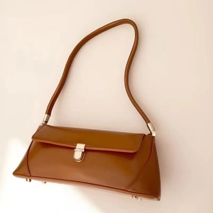 Retro brown leather baguette underarm bag with gold clasp and sleek minimalist design