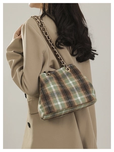 Detail of plaid tweed shoulder bag with golden chain strap on model's shoulder