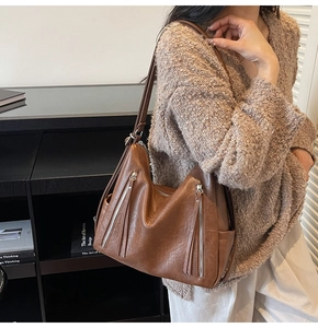 Brown faux leather shoulder bag with vertical zipper pockets and long tassel details