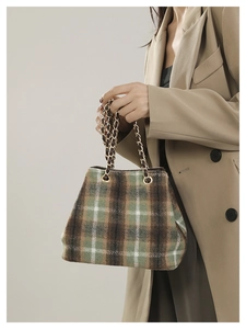 Detail of wool plaid handbag with gold eyelets and chain strap on khaki blazer