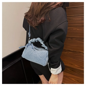 Close-up of light blue denim crossbody bag with ruched handle on a wooden staircase