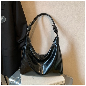 Detail of glossy black faux leather hobo bag with unique knotted strap and sleek finish