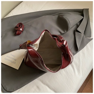 Internal view of burgundy glossy leather hobo bag with spacious lining on soft bedding