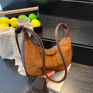 Sac hobo croissant en daim marron avec détail de poignée nouée sur fond sombre