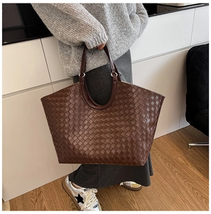 Detailed view of dark brown woven leather tote bag texture and curved handle design