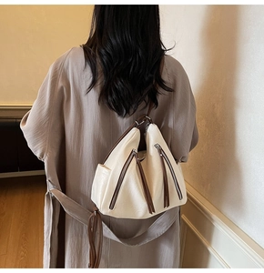 Detail view of a creamy white versatile backpack with vintage brown zipper accents