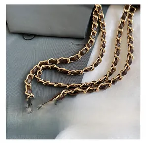 Detail of high-quality light gold metal chain interwoven with dark brown leather strap