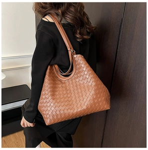 Detailed close-up of brown woven tote bag with Intrecciato pattern and long shoulder straps