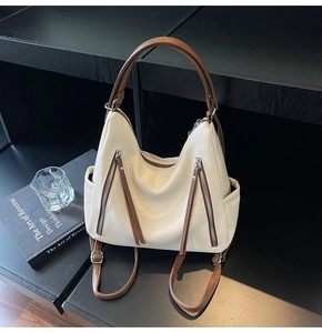 Detail of cream faux leather shoulder bag featuring brown straps and vertical zippers
