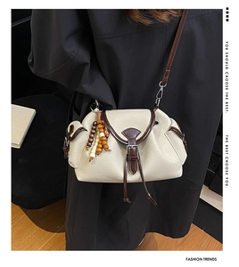 Détail du sac vintage en toile avec pompon en perles de bois et finitions en cuir marron