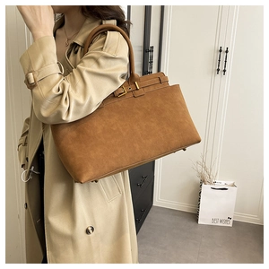Detail of caramel suede tote bag with belt buckle and metallic protective feet