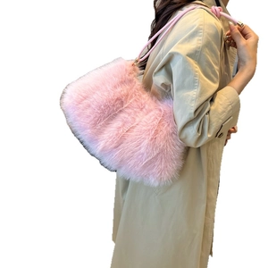 Sac à épaule en peluche rose avec texture douce et bandoulière en cuir sur trench-coat