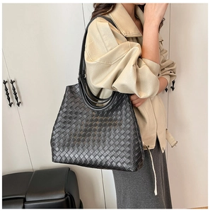 Detail shot of black woven tote bag showing leather texture and intricate braided pattern