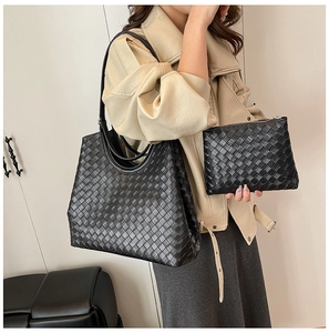 Detail of black woven tote bag and matching pouch showing intricate texture and scale
