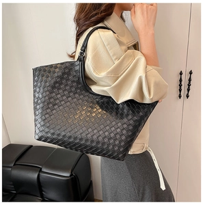 Detail of black woven leather tote bag with Intrecciato pattern and sturdy top handles