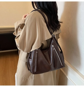 Detailed view of coffee brown tote bag with zipper accents on khaki trench coat