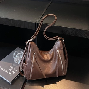 Detailed view of brown leather shoulder bag featuring stylish vertical metal zippers