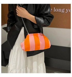 Détail du sac nuage en tricot rayé rose et orange avec chaîne en métal sur un mannequin