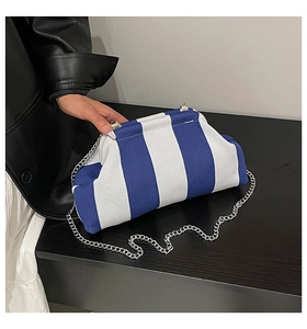 Détail de la pochette tissée rayée bleu et blanc avec fine chaîne argentée