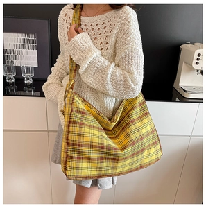 Detail of yellow plaid drawstring bag texture and wide strap on a minimal background